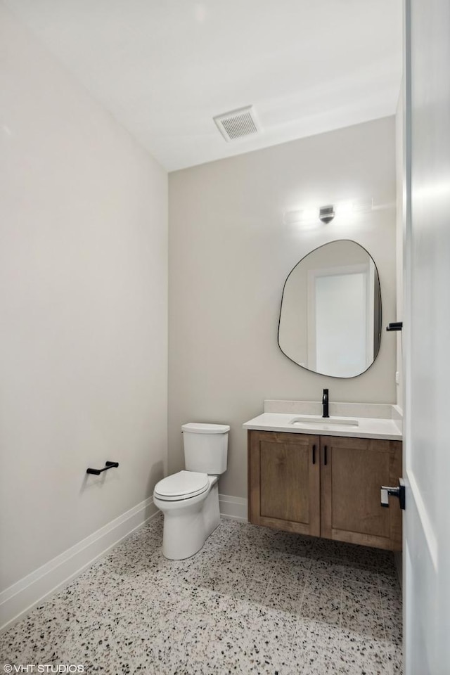 bathroom featuring visible vents, toilet, vanity, and baseboards