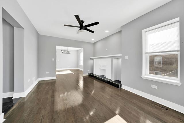 unfurnished living room with dark wood-type flooring and ceiling fan with notable chandelier