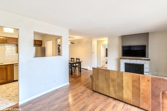 living room featuring ceiling fan, a fireplace, and light hardwood / wood-style flooring