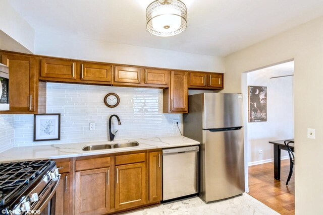 kitchen featuring dishwasher, sink, backsplash, and stainless steel refrigerator