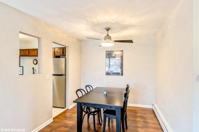 dining space with wood-type flooring, ceiling fan, and baseboard heating