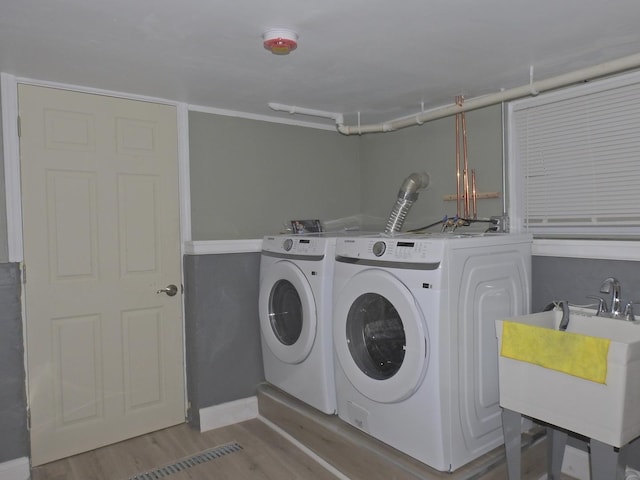 clothes washing area featuring separate washer and dryer, sink, and light wood-type flooring