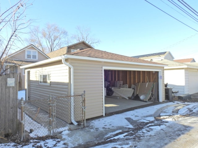 snow covered property with a garage and an outdoor structure