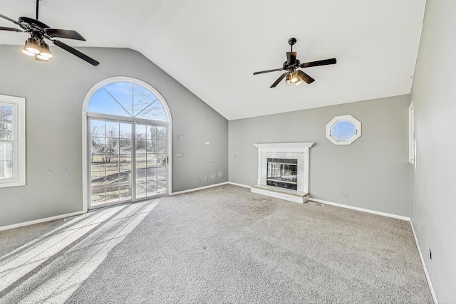 unfurnished living room featuring a tile fireplace, lofted ceiling, light colored carpet, and ceiling fan