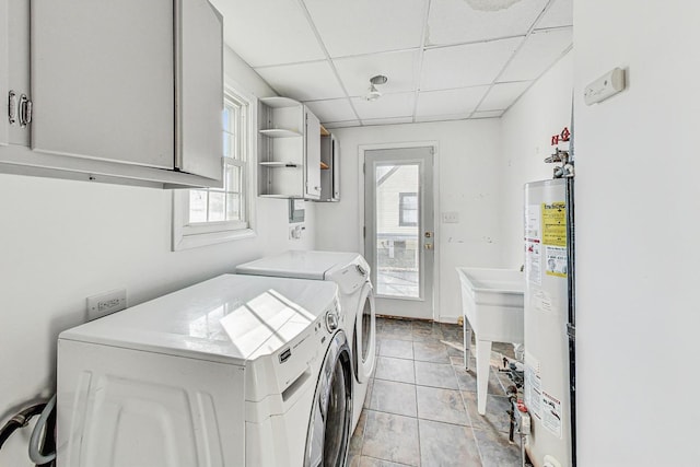 laundry area featuring light tile patterned flooring, sink, gas water heater, cabinets, and independent washer and dryer