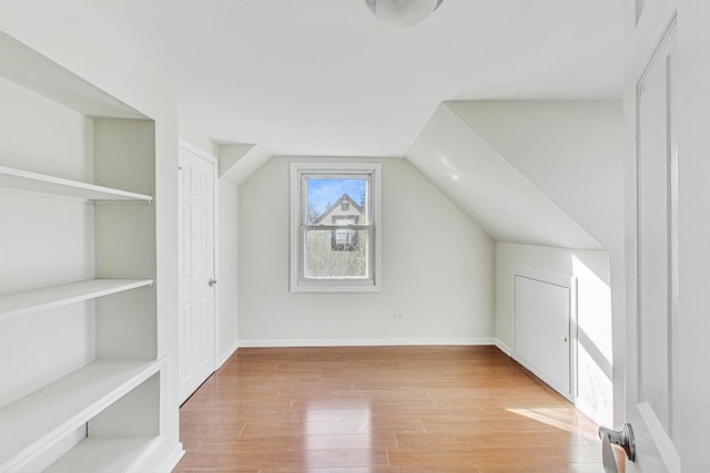 additional living space featuring light hardwood / wood-style flooring and vaulted ceiling