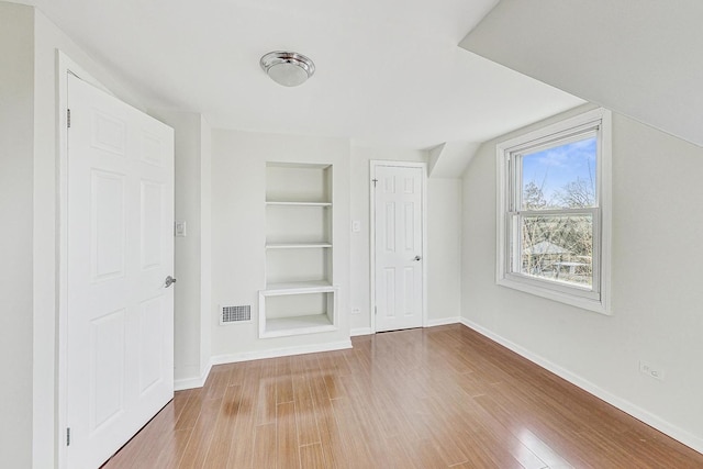 bonus room featuring built in features and light wood-type flooring