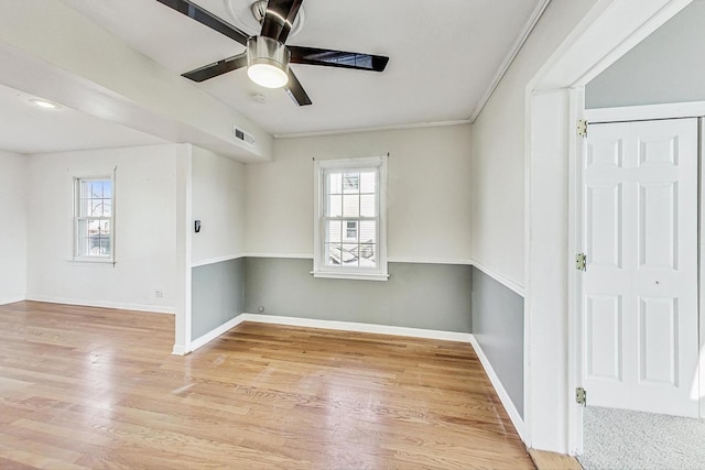 empty room featuring ceiling fan, a wealth of natural light, and light wood-type flooring