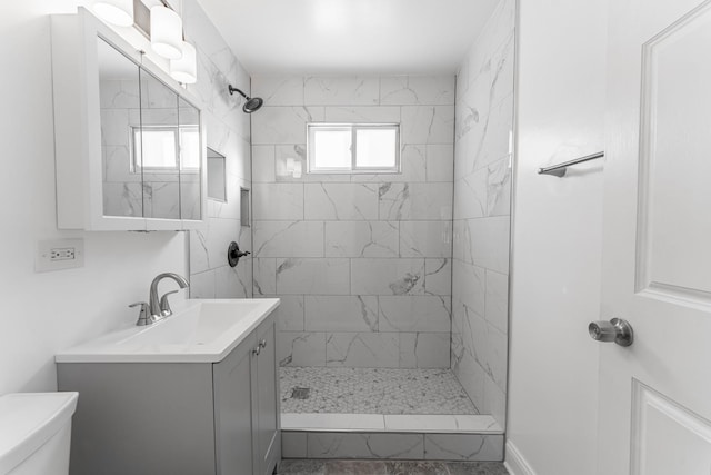 bathroom featuring vanity, toilet, and a tile shower