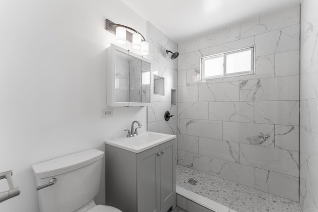 bathroom featuring vanity, toilet, and a tile shower