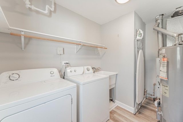 laundry room with light hardwood / wood-style flooring, washing machine and dryer, and water heater