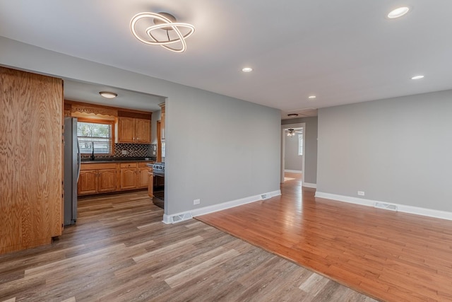 unfurnished living room with ceiling fan and light hardwood / wood-style flooring