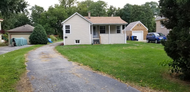 view of front of property featuring a garage, an outbuilding, a front yard, and covered porch