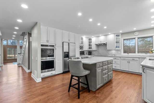 kitchen featuring a kitchen island, a breakfast bar, white cabinets, and appliances with stainless steel finishes