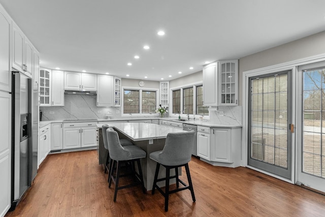 kitchen with a kitchen island, a breakfast bar, white cabinets, and appliances with stainless steel finishes