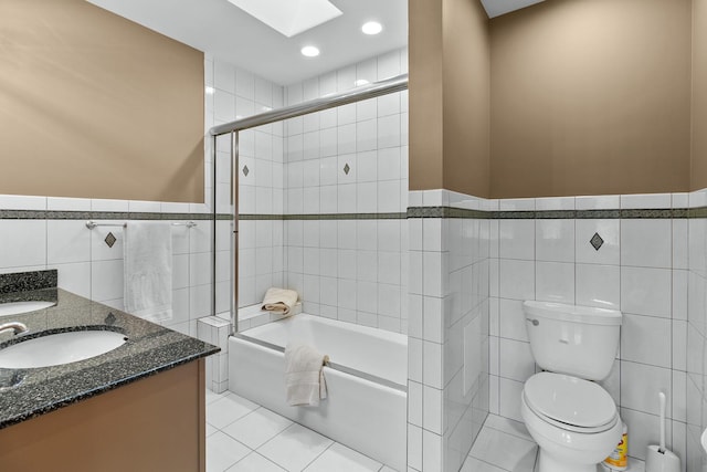 full bathroom featuring tile patterned floors, shower / bath combination with glass door, a skylight, tile walls, and vanity