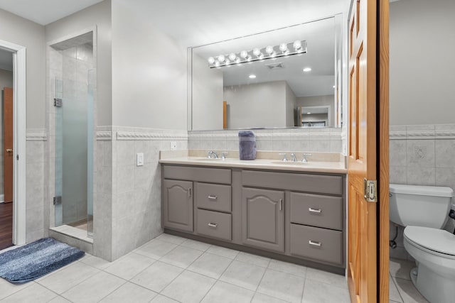 bathroom featuring walk in shower, toilet, tile patterned flooring, and tile walls