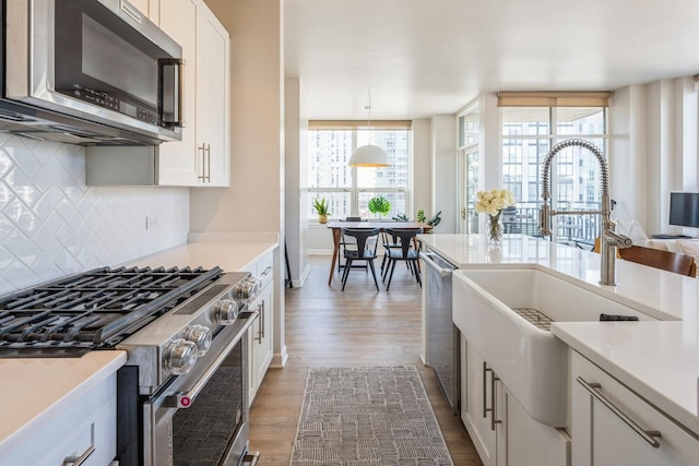 kitchen featuring white cabinetry, hanging light fixtures, stainless steel appliances, and hardwood / wood-style floors