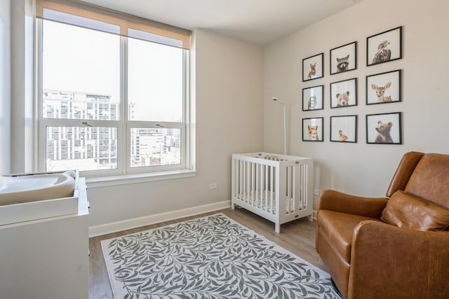 bedroom with light wood-type flooring and a nursery area