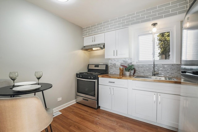 kitchen featuring sink, stainless steel gas range oven, tasteful backsplash, wooden counters, and white cabinets