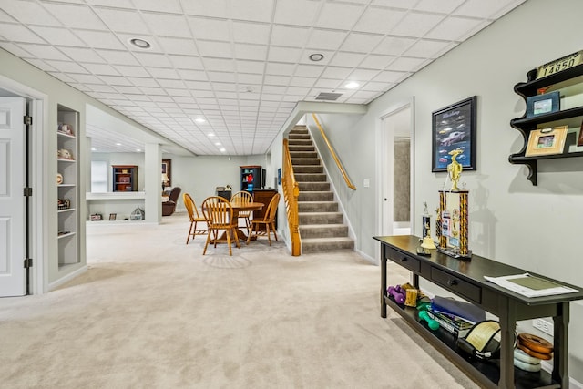 interior space featuring a drop ceiling, built in shelves, and carpet flooring