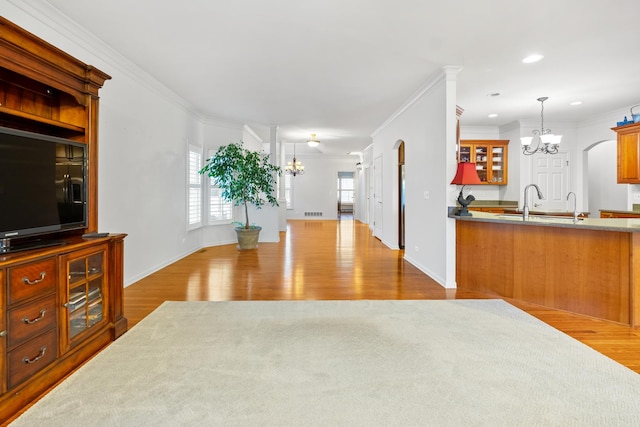 kitchen featuring an inviting chandelier, decorative light fixtures, ornamental molding, and light wood-type flooring