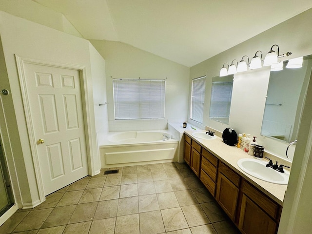 bathroom featuring a washtub, vanity, vaulted ceiling, and tile patterned floors