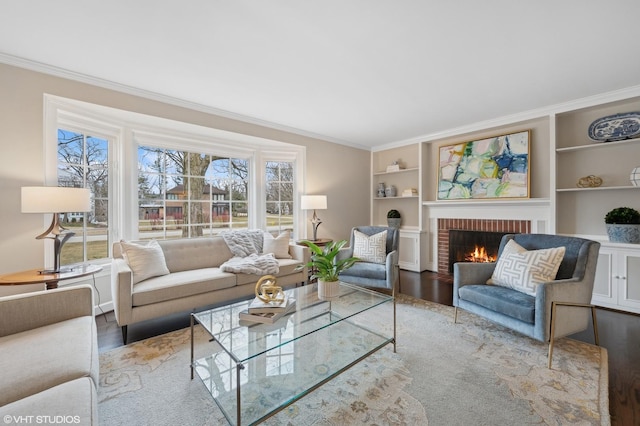 living room featuring hardwood / wood-style floors, built in features, ornamental molding, and a brick fireplace