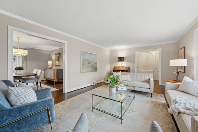 living room featuring hardwood / wood-style flooring, ornamental molding, and an inviting chandelier