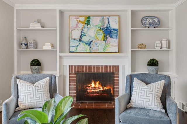 living area with dark wood-type flooring, ornamental molding, a fireplace, and built in features