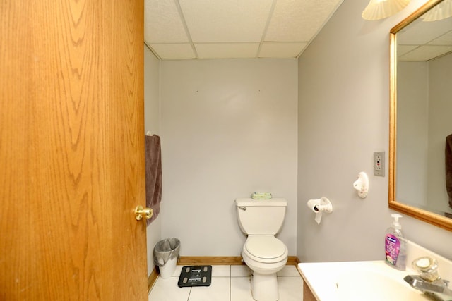 bathroom featuring vanity, a drop ceiling, tile patterned floors, and toilet