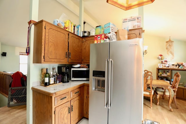 kitchen featuring tile countertops, high end refrigerator, and light hardwood / wood-style flooring