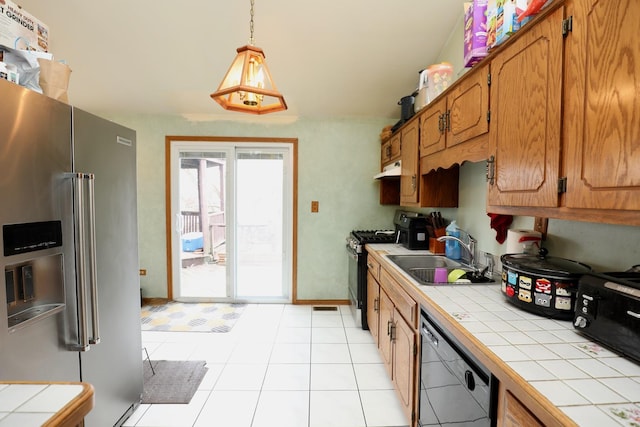 kitchen with sink, range with gas cooktop, tile countertops, high quality fridge, and dishwasher