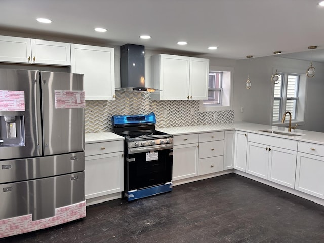 kitchen featuring appliances with stainless steel finishes, white cabinetry, sink, hanging light fixtures, and wall chimney range hood