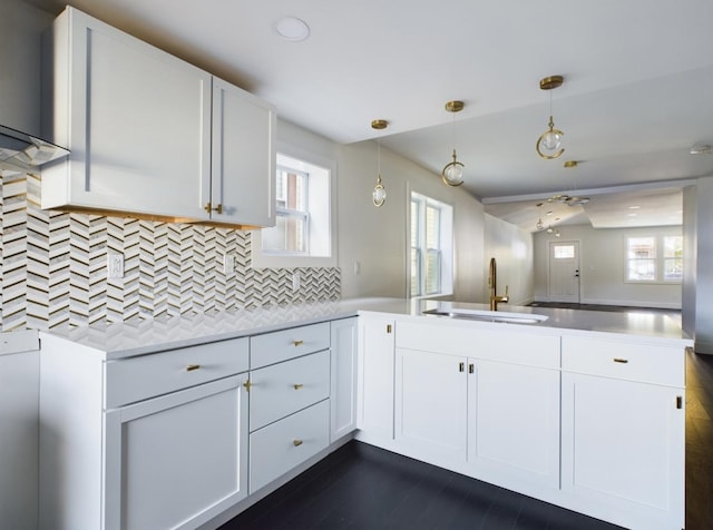 kitchen with white cabinetry, sink, backsplash, hanging light fixtures, and kitchen peninsula