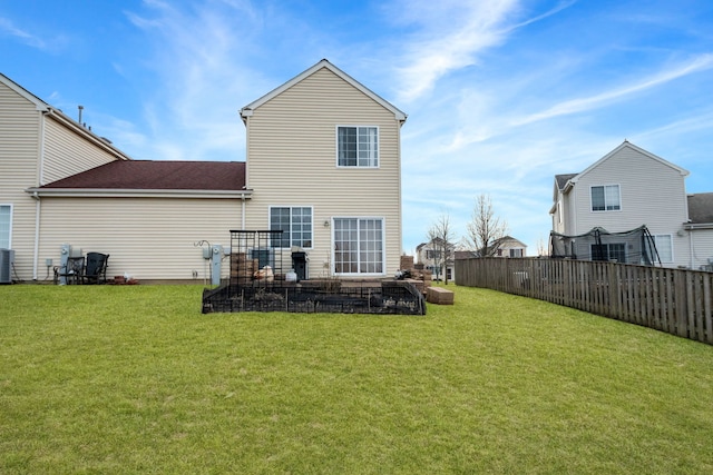 rear view of property featuring a trampoline, a yard, and central air condition unit