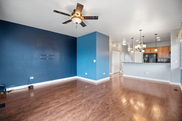 unfurnished living room with dark hardwood / wood-style floors and ceiling fan with notable chandelier