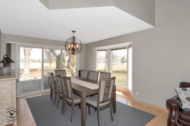 dining room with light wood-style floors, a healthy amount of sunlight, a notable chandelier, and baseboards