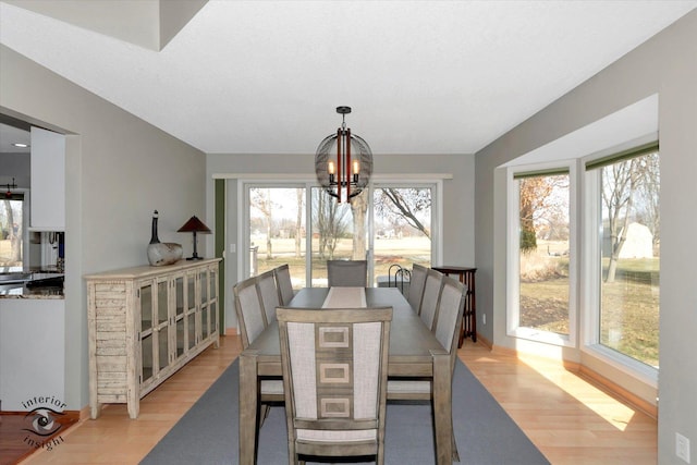 dining area with a chandelier, baseboards, and light wood finished floors