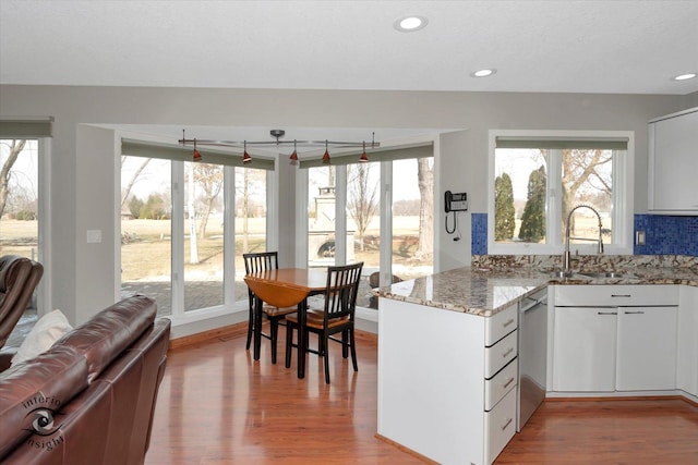 kitchen with light stone countertops, a sink, a peninsula, and wood finished floors