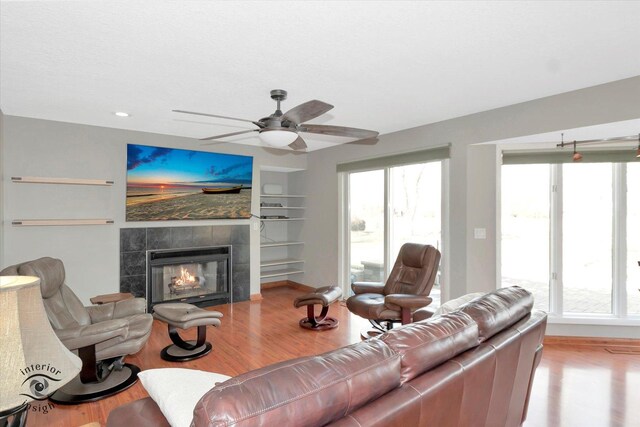 living room featuring plenty of natural light, a tiled fireplace, and wood finished floors