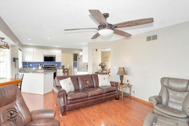 living area featuring recessed lighting, visible vents, light wood-style flooring, a ceiling fan, and baseboards