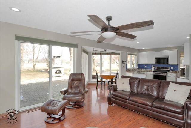 living room with visible vents, a ceiling fan, wood finished floors, a textured ceiling, and recessed lighting