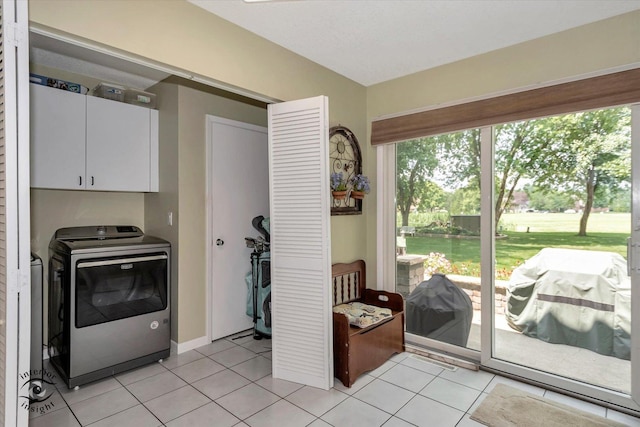 doorway to outside with light tile patterned flooring, washing machine and clothes dryer, and baseboards