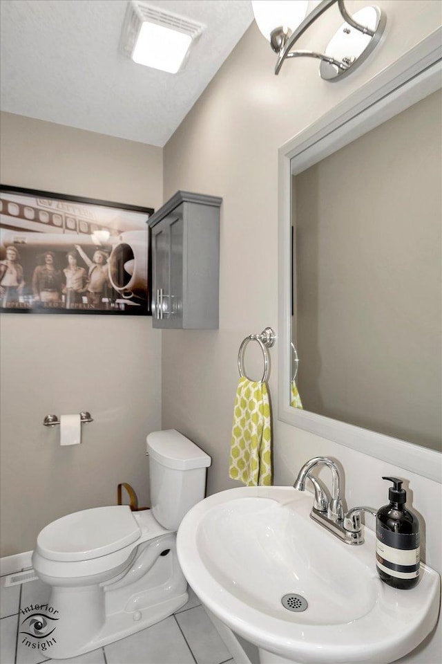 half bath with toilet, vaulted ceiling, a sink, and tile patterned floors