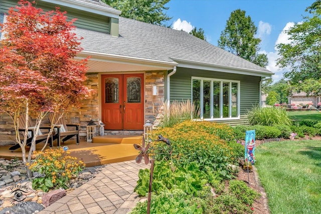 entrance to property with covered porch, stone siding, and roof with shingles