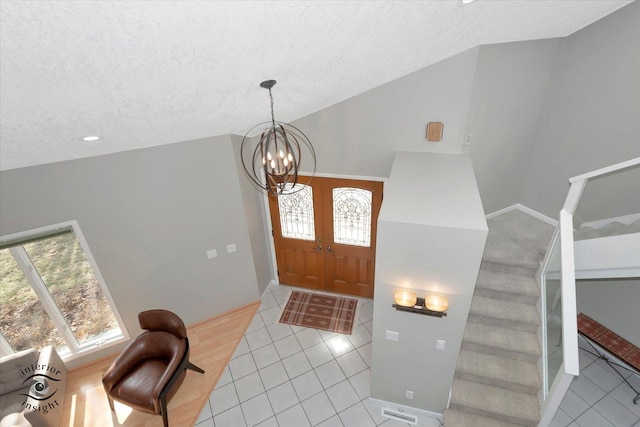 foyer with lofted ceiling, light tile patterned floors, stairs, and a wealth of natural light