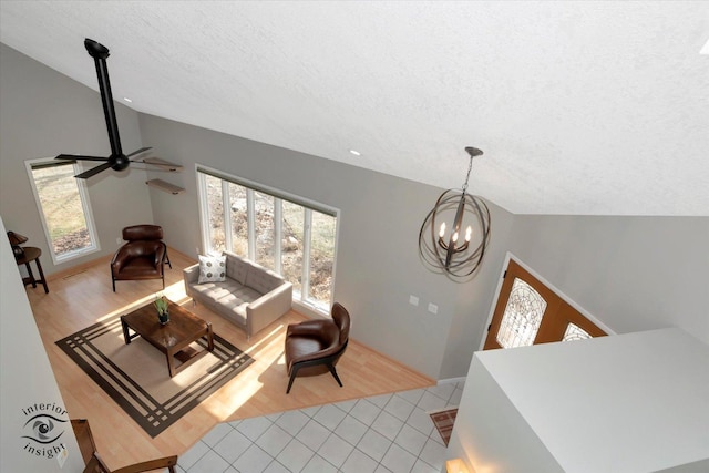 living area featuring lofted ceiling, light tile patterned flooring, plenty of natural light, and a textured ceiling