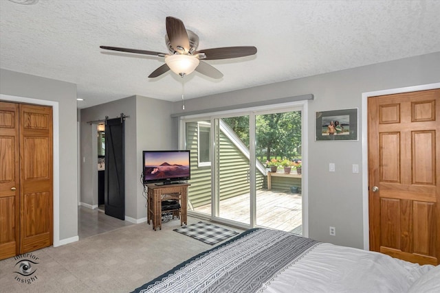 carpeted bedroom with a barn door, baseboards, a ceiling fan, access to outside, and a textured ceiling