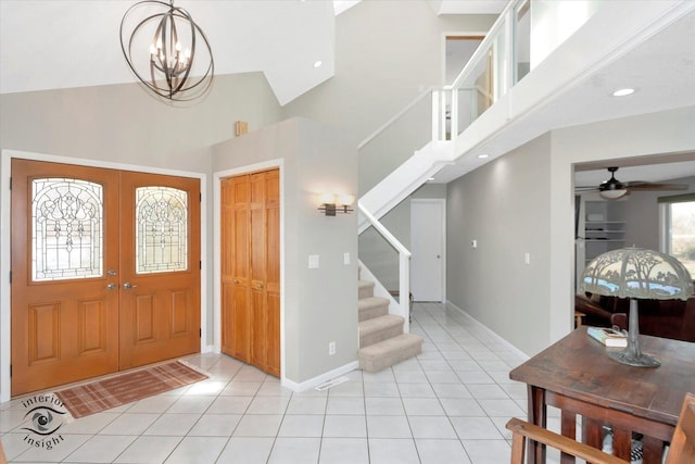 foyer featuring light tile patterned floors, high vaulted ceiling, stairway, and baseboards